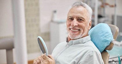 senior man smiling brightly in the dental chair 