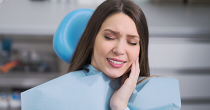 Woman in dental chair holding cheek