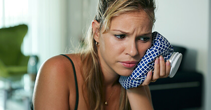 Woman holding ice pack to her  cheek