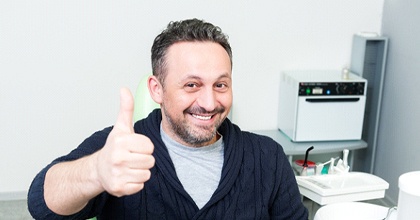 Happy dental patient, giving thumbs up for full mouth reconstruction