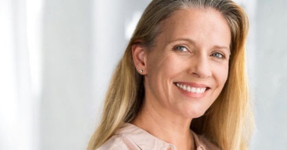 Smiling, mature woman with implant dentures in Bristol