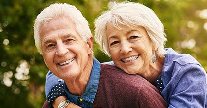 senior man and woman hugging each other outdoors