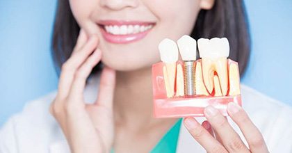 dentist holding a model of a dental implant in the jaw