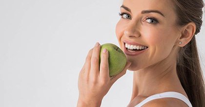 woman biting into a green apple