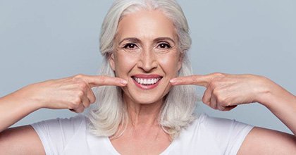 senior woman pointing to her smile