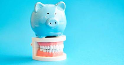 light blue piggy bank atop a set of false teeth