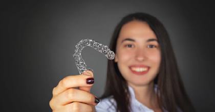 Woman holding up an Invisalign tray