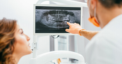 Dentist and patient examine panoramic smile x-rays