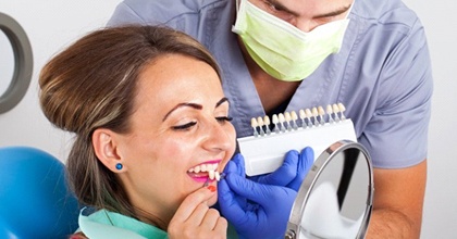 woman in red shirt trying on veneers with dentist