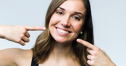 Woman pointing to her smile