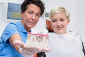 dentist holding dental implant model