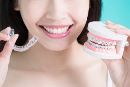 Woman holding braces in one hand and Invisalign in another