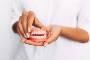 Woman holding a broken denture that has been repaired