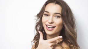 Woman with brown hair wearing mauve lipstick smiling