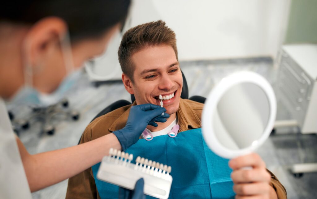 A man at the dentist selecting a shade of veneers.